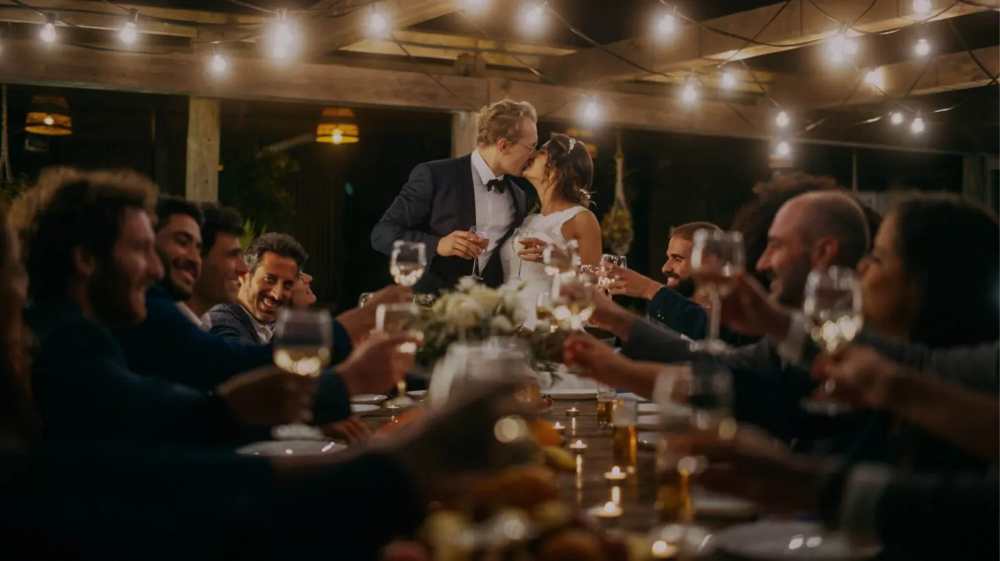 Bride and groom toasting at a long candlelit table